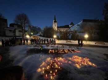 Vor der Kirche von Mariazell bei Dunkelheit stehen Teelichter die "M-Zell" schreiben