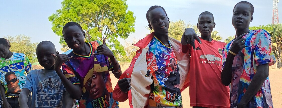 eine Gruppe junger südsudanesischer Burschen grinst und macht coole Posen für die Kamera.