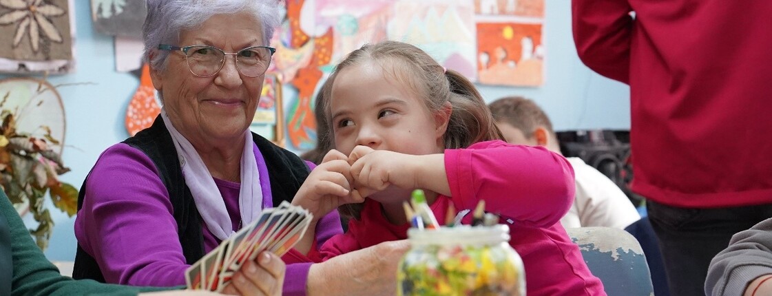 Eine freiwillige Mitarbeiterin spielt mit einem Kind UNO