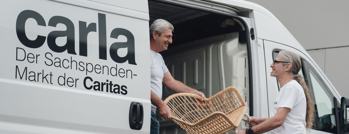 Männer vom Carla Transportteam heben Sessel in den Carla Transportbus