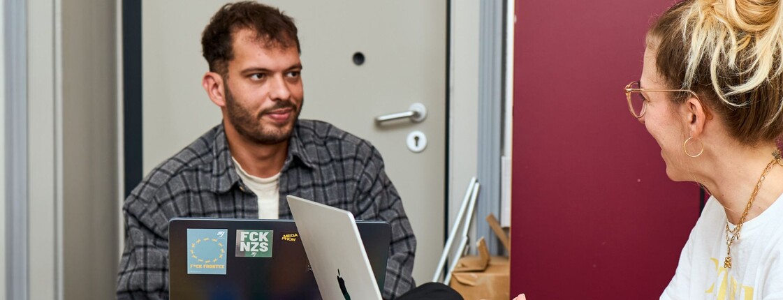 Zwei Freiwillige des Caritas Steiermark sitzen an einem Tisch