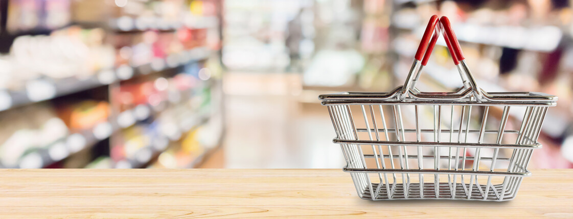 Empty Shopping basket on wood table over grocery store supermarket blur background