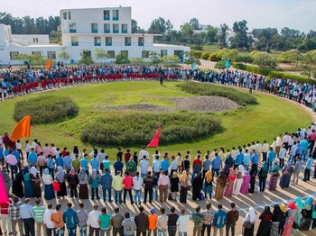 Campus Gespräche Sekem Ägypten Eine große Menge von Menschen steht im Kreis rund um einen Garten.