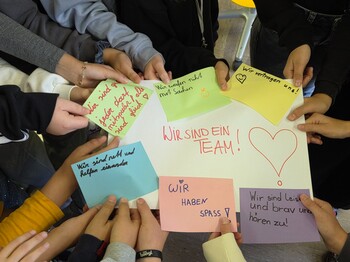 Hände, die ein beschriftetes Plakat und Zettel halten