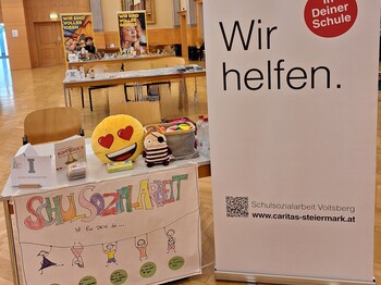 Infotisch der Schulsozialarbeit mit Plüschtieren, Broschüren und einem Banner der Caritas