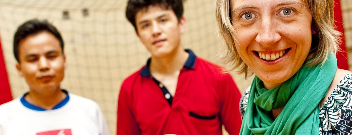 Eine Betreuerin und zwei junge Männer mit einem Fußball