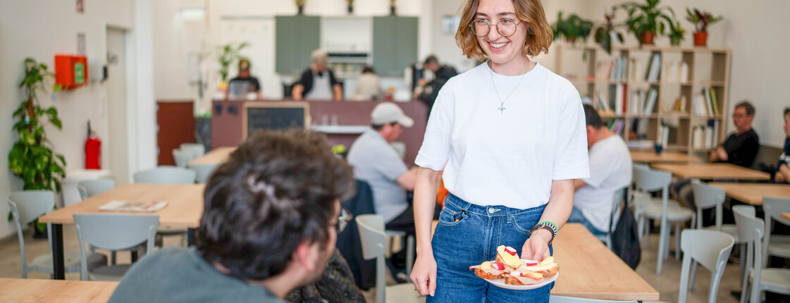 In der Bahnhofsmission bringt eine Freiwillige einem Besucher Essen