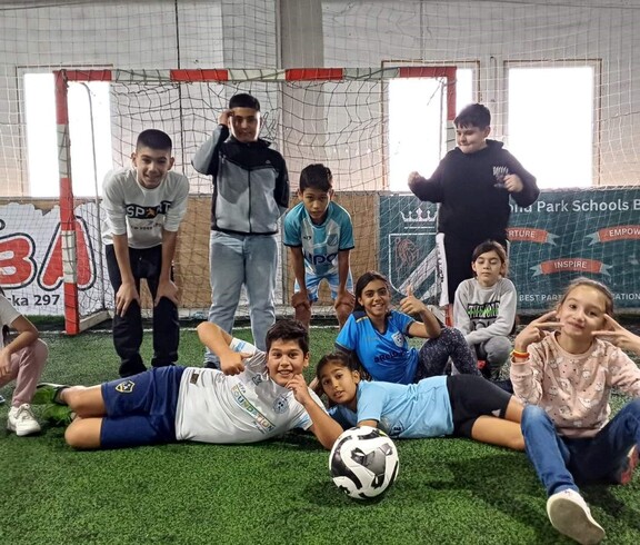 Kinder posieren mit Fußball vor dem Fußballtor