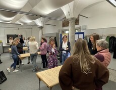 Die Erasmus-Teilnehmenden stehen an verschiedenen Schreibtischen verteilt und diskutieren. 