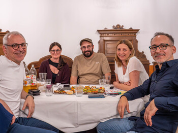 Eine Gruppe von Menschen, die an einem Tisch sitzt und in die Kamera schaut
