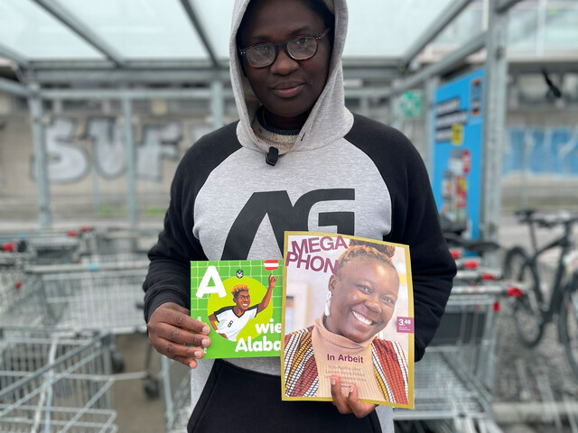 Eine Megaphon Verkäuferin mit dem neuen Megaphon Kinderbuch zur Fußball-WM