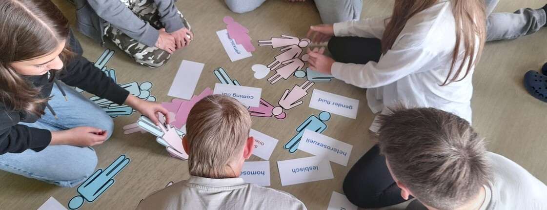 Jugendliche von oben im Kreis am Boden sitzend mit Unterlagen des Workshops in der Mitte