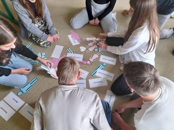 Jugendliche von oben im Kreis am Boden sitzend mit Unterlagen des Workshops in der Mitte