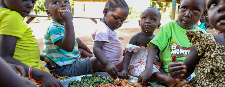 Hilfe gegen Hunger für Kinder in Afrika: Kinder sitzen um einen gefüllten Teller