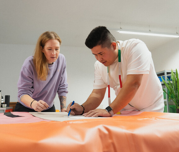 Ein Jugendlicher zeichnet ein Schnittmuster auf einen Plane