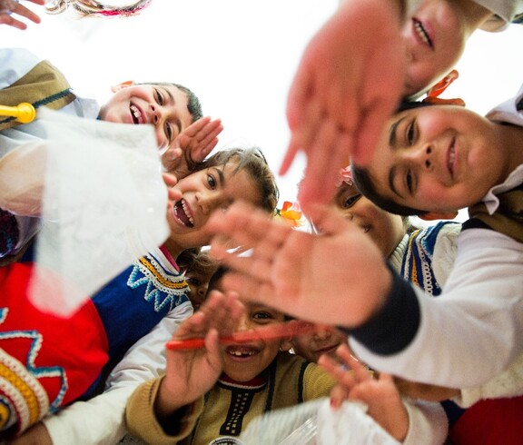 Kinder sitzen an Tischen und lernen