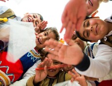 Kinder sitzen an Tischen und lernen