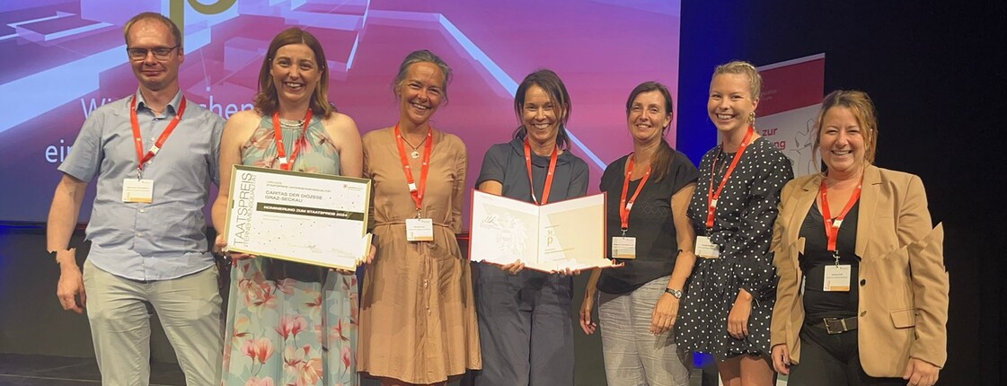 Das Team der Caritas auf der Bühne bei der Verleihung des Staatspreis Unternehmensqualität