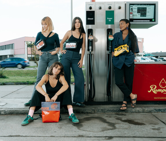 Jugendliche mit tag.werk Taschen und Rucksäcken bei einer Tankstelle