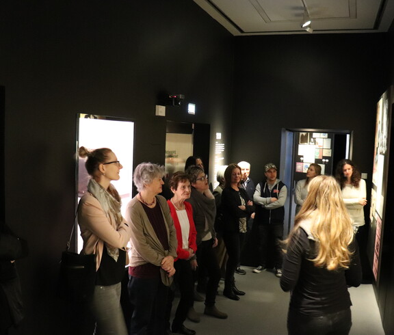 Eine Gruppe von Menschen besucht ein Museum und betrachtet ein Kunstwerk.