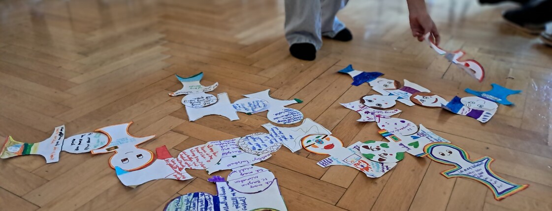 Eine Papiergirlande mit Zeichnungen und Notizen aus dem Workshop am Boden eines Raumes