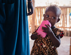 Ein südsudanesisches Kleinkind trinkt aus einem rosa Becher. 