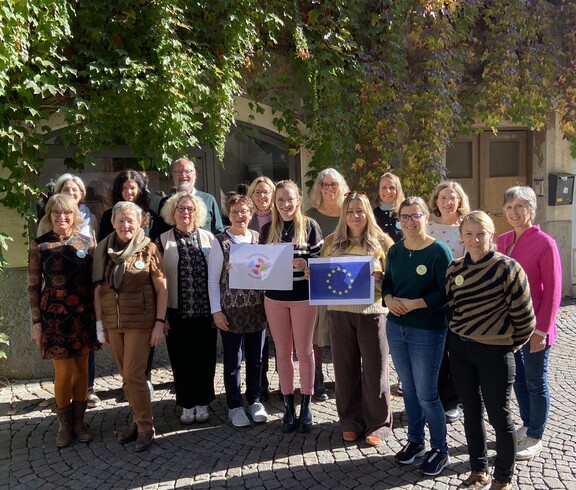 Gruppenfoto der Erasmus Teilnehmenden. 2 Personen halten das Logo des Projekts "Gemeinsam Engagiert" und die EU Flagge in der Hand. 