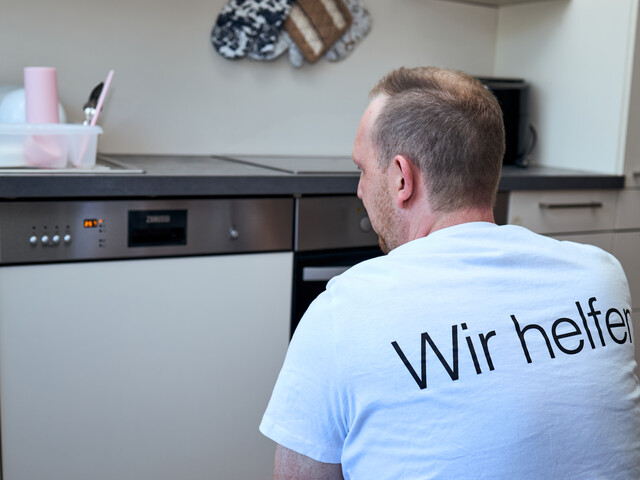 Ein Mitarbeiter der Caritas Energiesparberatung sieht sich ein altes Geschirrspülgerät an.