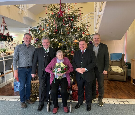 Hausleiter Josef Url, Bürgermeister ÖkR Josef Niggas, Vizebürgermeister Robert Sauer und BPO 2. Landtagspräsident Werner Amon, MBA, stehen nebeneinander und posieren für ein Gruppenfoto. In der Mitte steht Frau Markl, die einen Blumenstrauß in den Händen hält. Hinter der Gruppe ist ein festlich geschmückter Christbaum zu sehen. Die Personen blicken freundlich in die Kamera und stehen in einem offiziellen oder feierlichen Rahmen zusammen. 