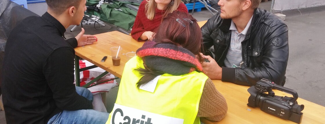 Litauische Journalisten sprechen mit Caritas Mitarbeiterin und Flüchtling