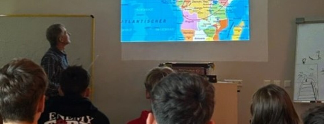 Schüler*innen blicken auf die Projektion des Bildes einer Afrikakarte. 