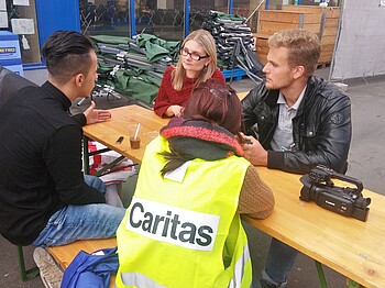 Litauische Journalisten sprechen mit Caritas Mitarbeiterin und Flüchtling