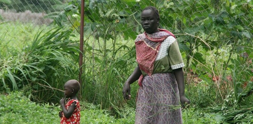 Afrikanische Frau mit Kind bei der Arbeit am Feld