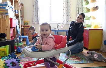 Zwei Kleinkinder mit einer Mutter in einem Spielraum