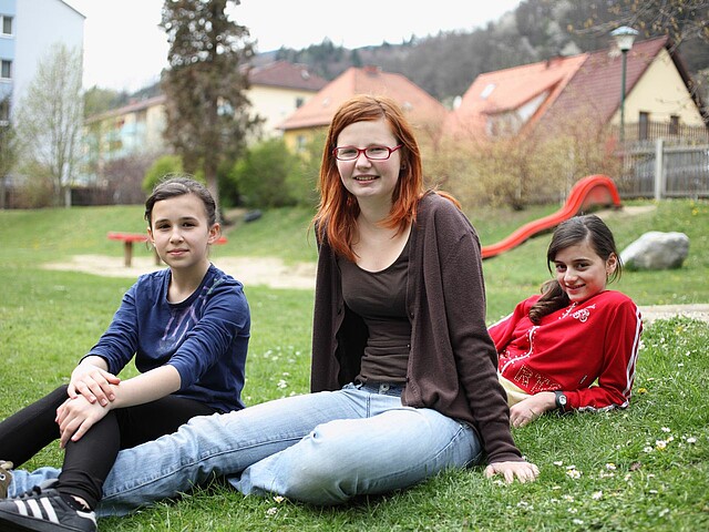Drei Mädchen sitzen auf einer Wiese