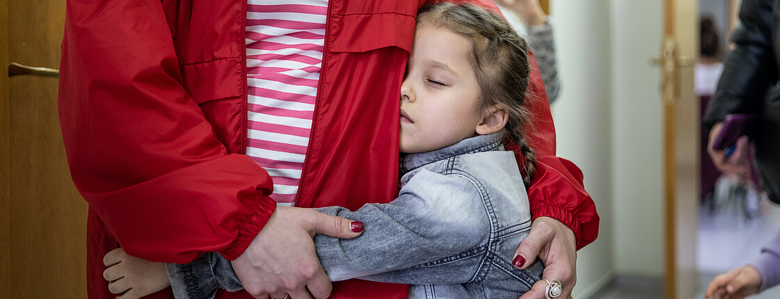 Kind umarmt eine Mitarbeiterin der Caritas Moldova.